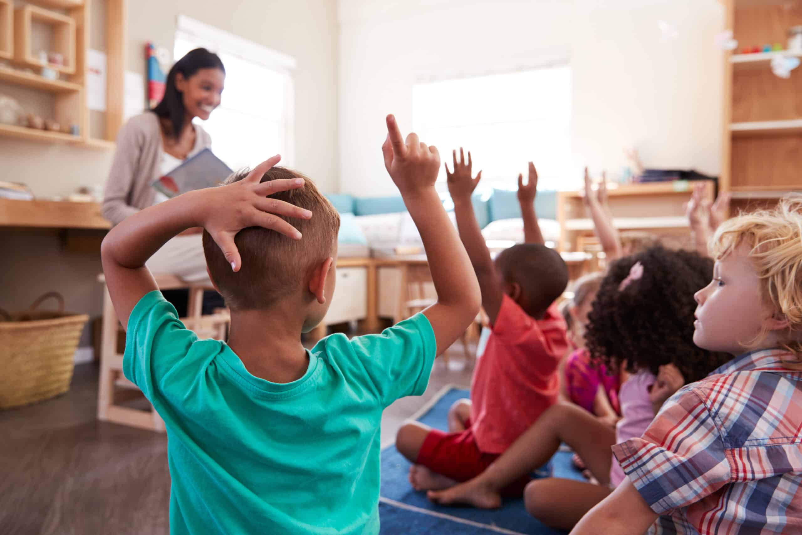 Pupils,at,montessori,school,raising,hands,to,answer,question