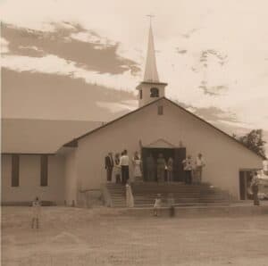 Historical photo of Pahrump Community Church exterior with members  gathered around the entrance.