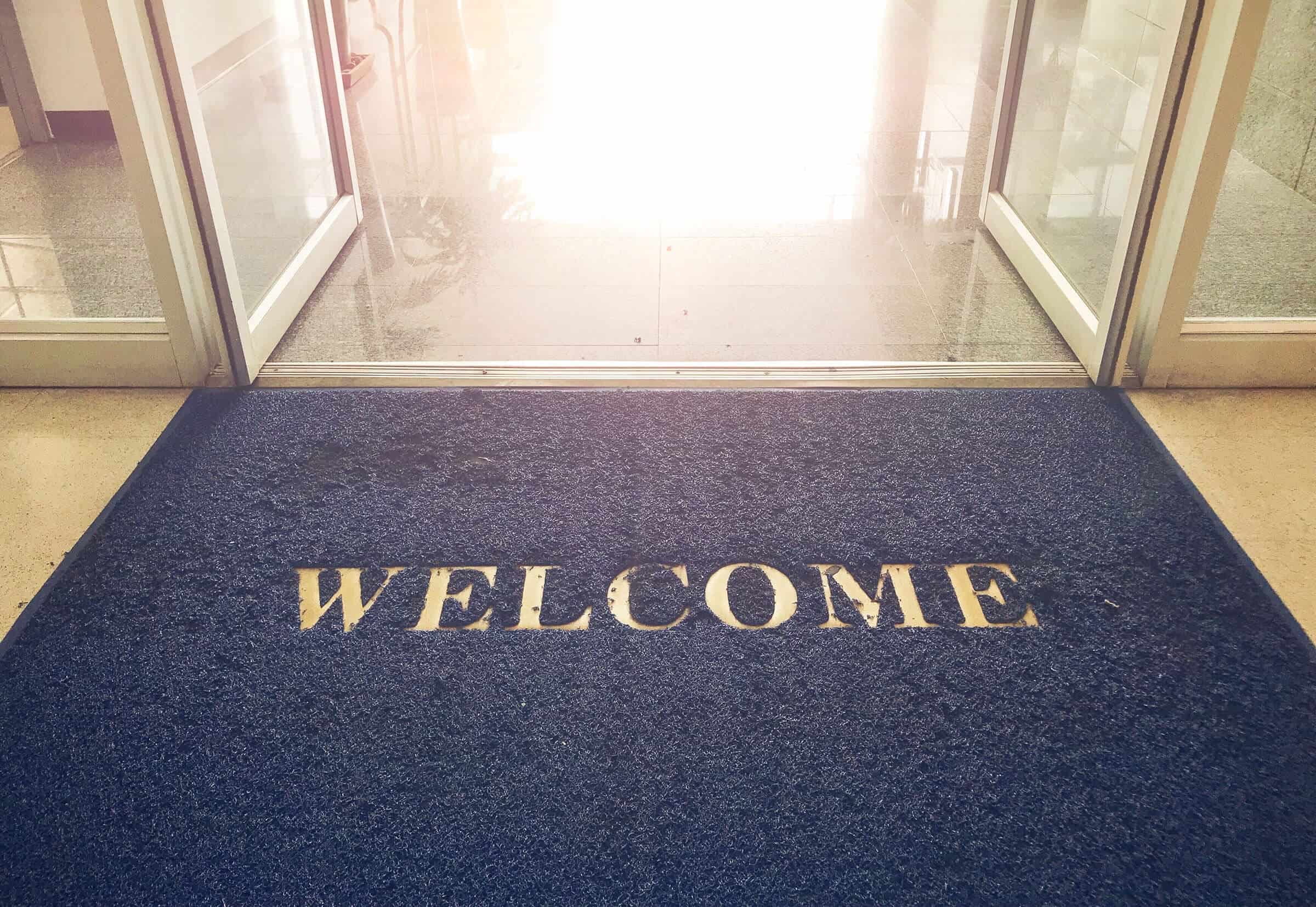Decorative banner featuring a stock photo welcome blue mat in front of door